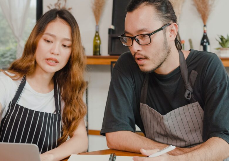 Asian small business owners couple using laptop discussing project and finance.